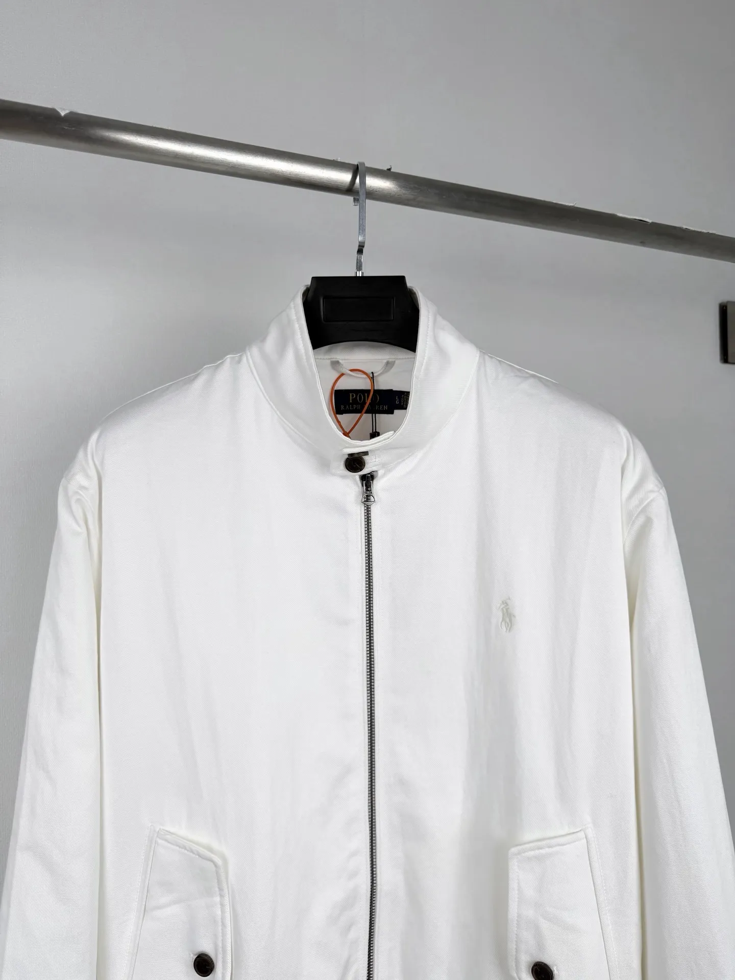 Ralph Lauren embroidered zipper jacket, custom obsidian bamboo honking oblique brocade, crisp and stylish, warm and skin-friendly, radiant milky white spreads over the body, the texture slowly unfolds with the light and shadow, showing unobtrusive classic elegance, exquisite pony embroidery on the left chest, dense and regular stitching, engraved with the brand's handed down totem, concealing the edge, and bringing with it timeless recognition. The neat stand-up collar is embellished with Retro brown buttons. The diagonal pockets are matched with ribs to create a short and relaxed silhouette. Between the plain white body, it embodies the restrained and elegant style of American old money. Process 1: Using imported machine embroidery technology. Using advanced computer control systems and precision mechanical components to achieve the iconic pony embroidery operation. High precision. The lines are smooth and delicate. Process 2: Template machine bag opening. Preset templates guide the position of opening the bag. The accuracy of the shape and size ensures the quality of the bag opening effect. Process 3: The fabrics have been fermented and washed. The hand feel and texture are better. Not easy to deform. Not easy to shrink. Not easy to fade. Maintain long-term beauty. Accessories: Customized 1:1 Ralph Lauren resin buckle. Customized 1:1 Ralph Lauren zipper. Customized 1:1 Genuine Leather lanyard. Customized 1:1 Ralph Lauren trademark. Version: Loose version Size: S M L XL